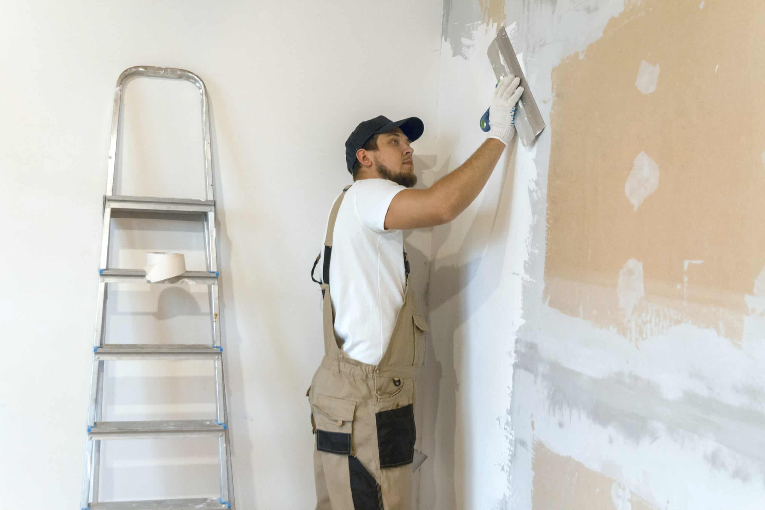Drywall repair technician in Edmonton smoothing joint compound over a patched wall in a Grovenor Edmonton home interior.