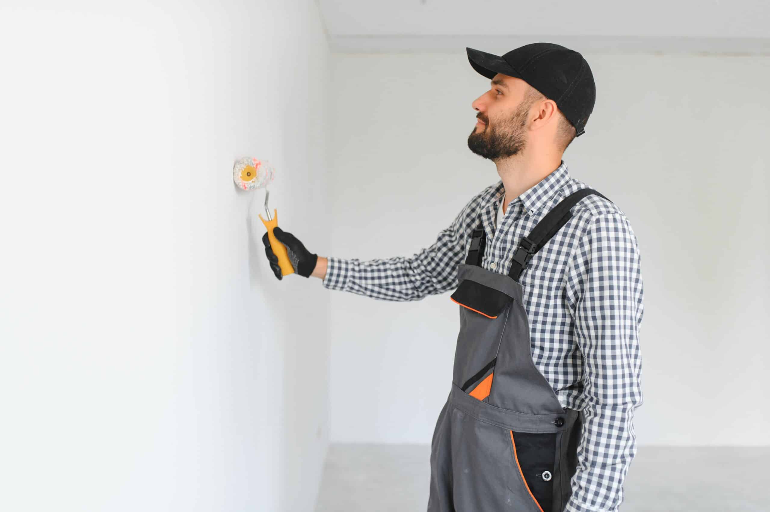 Interior house painters Edmonton rolling fresh paint on a Bonnie Doon Edmonton bedroom wall with trim taped off.