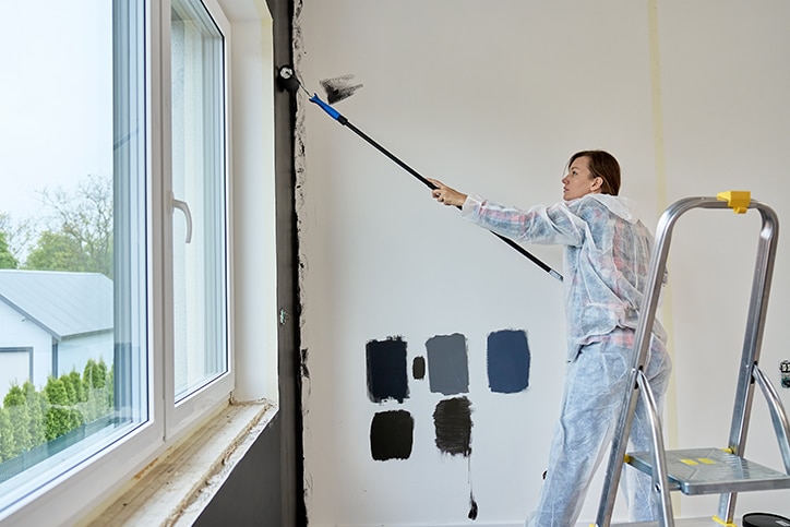 Interior house painters Edmonton cutting in fresh white paint along crown moulding in a Strathcona Edmonton living room.